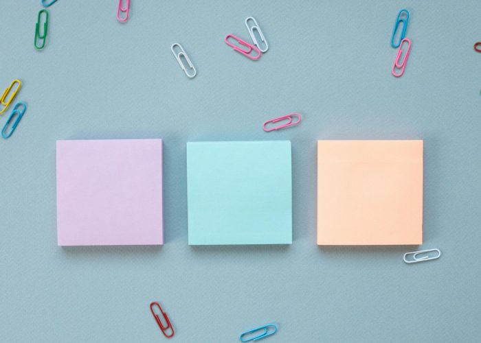 Vibrant pastel Post-It Notes with playful paperclips on a blue backdrop.